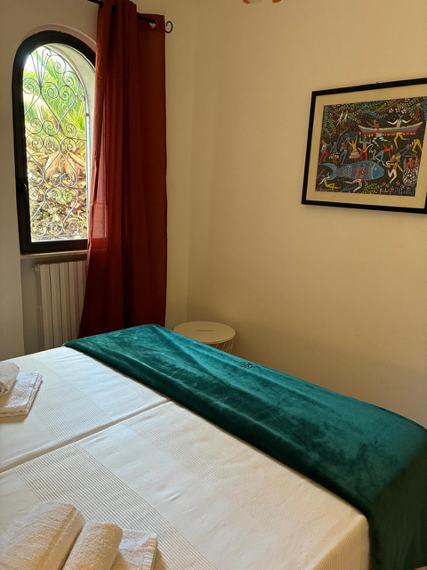 Camera da letto con coperta verde e finestra ad arco