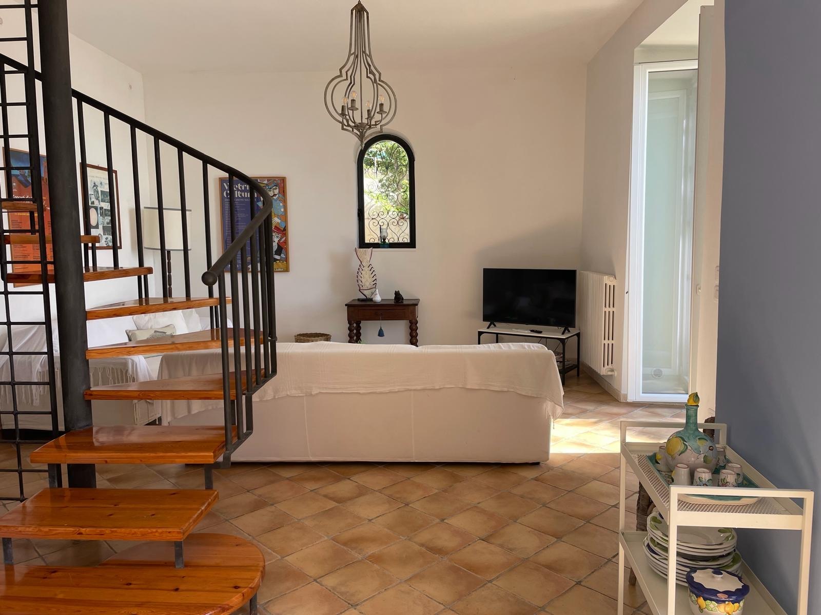 Soggiorno con scala interna, lampadario e pavimento in cotto